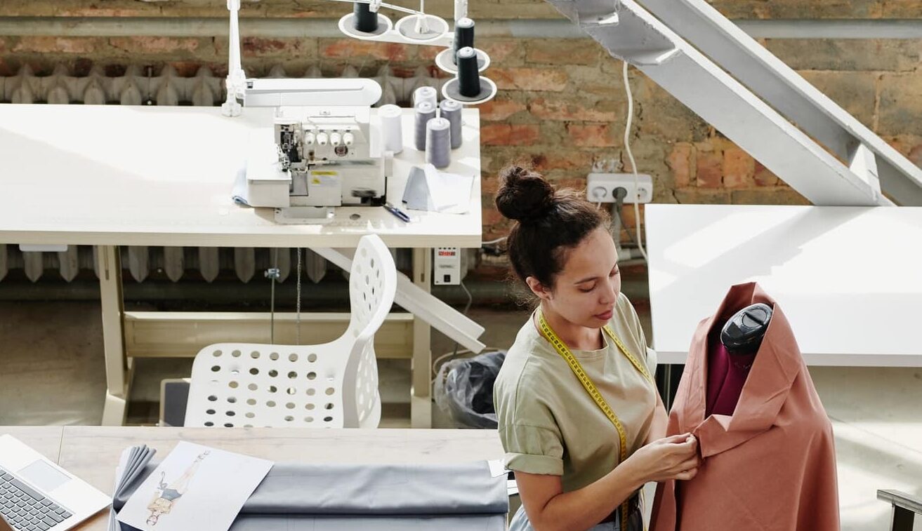 Young contemporary fashion designer working with textile on dummy