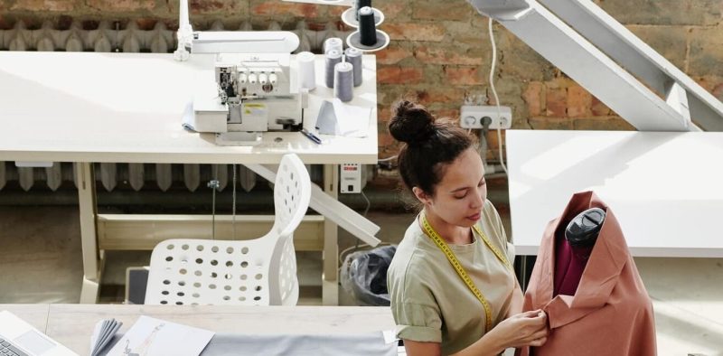 Young contemporary fashion designer working with textile on dummy
